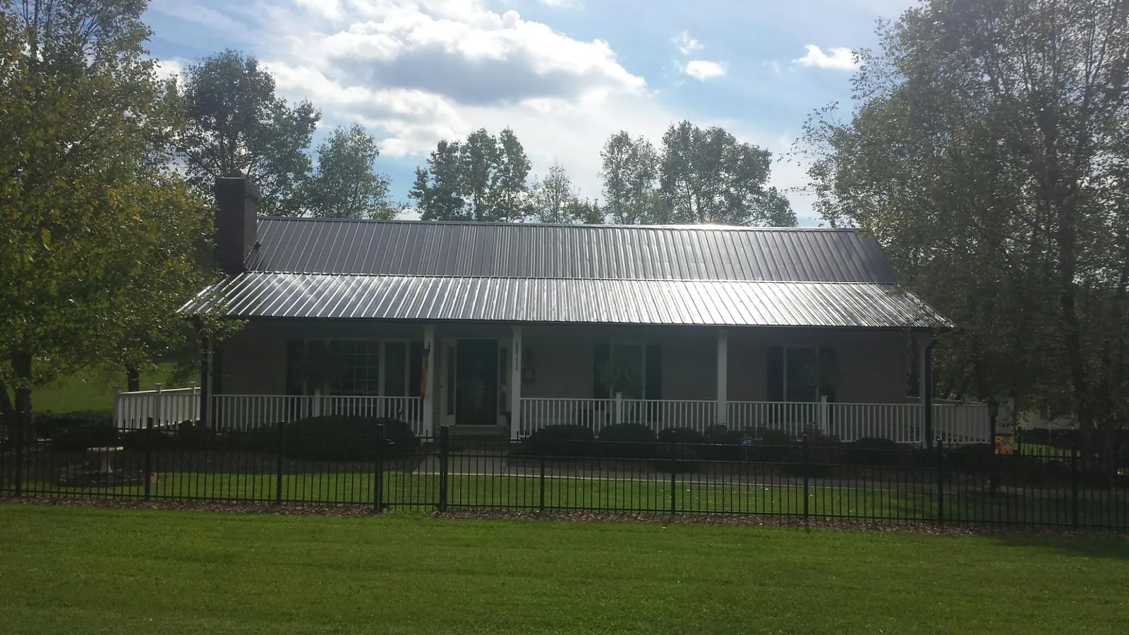 Gray metal roof on a brick ranch with a full width front porch — Gutter Guard Installation work by our crew in Jeffersonville
