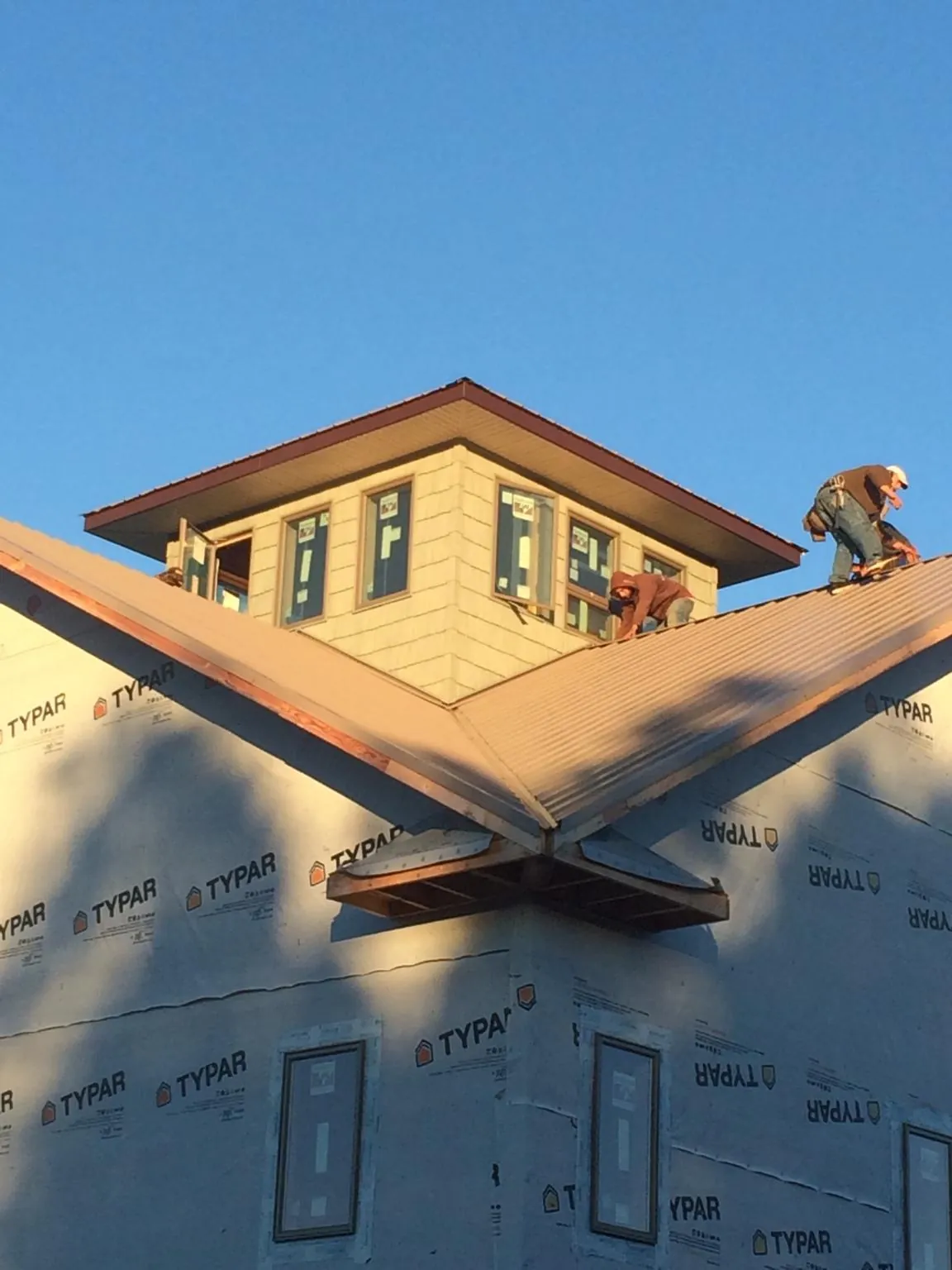 Roofers working around a rooftop cupola on a new metal roof at sunset — Roof Waterproofing in Jeffersonville by Roofing Brothers